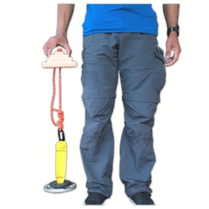 May include: A yellow and orange climbing anchor with a rope and a wooden block. The anchor is attached to a metal ring.