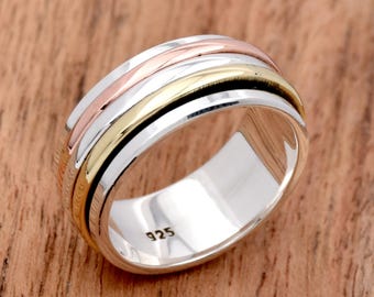 May include: A silver spinning ring with three bands of gold and rose gold. The ring is marked with the number "925" on the inside.