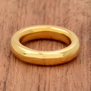 Puede incluir: Un anillo de banda de oro simple con un acabado liso y pulido.