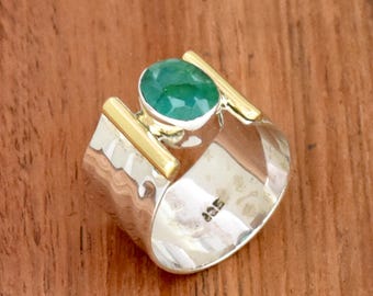 May include: A silver ring with a green gemstone set in a gold band. The ring has a hammered texture and is marked with the number "925".