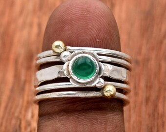 May include: A silver ring with a green gemstone and gold accents. The ring is made of multiple bands and has a delicate floral design.