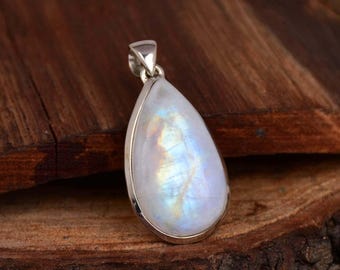 May include: A pear-shaped pendant with a polished, iridescent moonstone. The stone is set in a silver bezel and has a shimmering, milky white and blue color. The pendant is suspended from a silver bail.