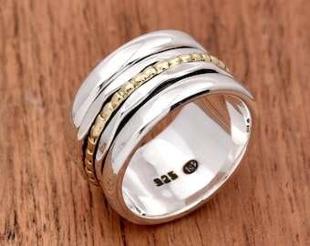 May include: A silver and gold spinning ring with a textured band. The ring has a 925 stamp on the inside.