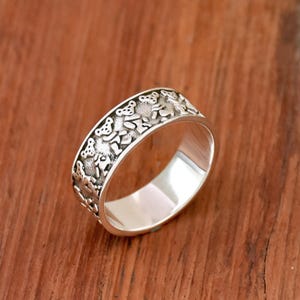 May include: A silver band ring with a design of dancing bears around the entire band.