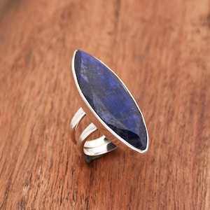 May include: A silver ring with a large, dark blue, marquise-shaped gemstone.