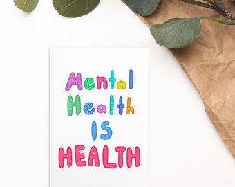 May include: A white card with the text "Mental Health Is Health" in colorful, stylized lettering.