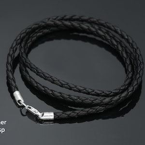 May include: A black braided leather cord necklace with a silver clasp.