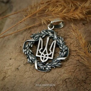 May include: Silver pendant featuring the Ukrainian coat of arms, a trident, surrounded by a wreath of wheat.