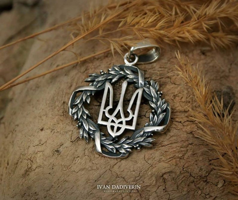 May include: Silver pendant featuring the Ukrainian coat of arms, a trident, surrounded by a wreath of wheat.