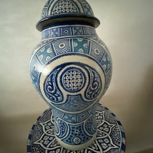 以下が含まれることがあります： 蓋と底が揃った青と白の陶器の壺。壺は複雑な幾何学模様で飾られています