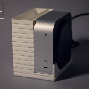 May include: A contemporary device featuring a white, ribbed base and a silver-coloured top section. It incorporates a black circular component and the text "stratalique." within a white box. The design is sleek and minimalist.