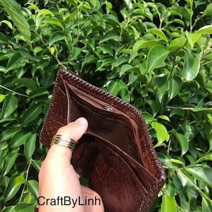 May include: A brown leather wallet with a crocodile pattern and a zipper closure. The wallet is open and empty, showing the interior lining. The text "CraftByLinh" is visible on the wallet.