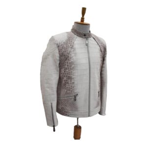 Puede incluir: Chaqueta de cuero blanca y gris con estampado de cocodrilo. La chaqueta tiene cierre de cremallera, cuello alto y bolsillos con cremallera. La chaqueta se exhibe en un maniqu&iacute;.