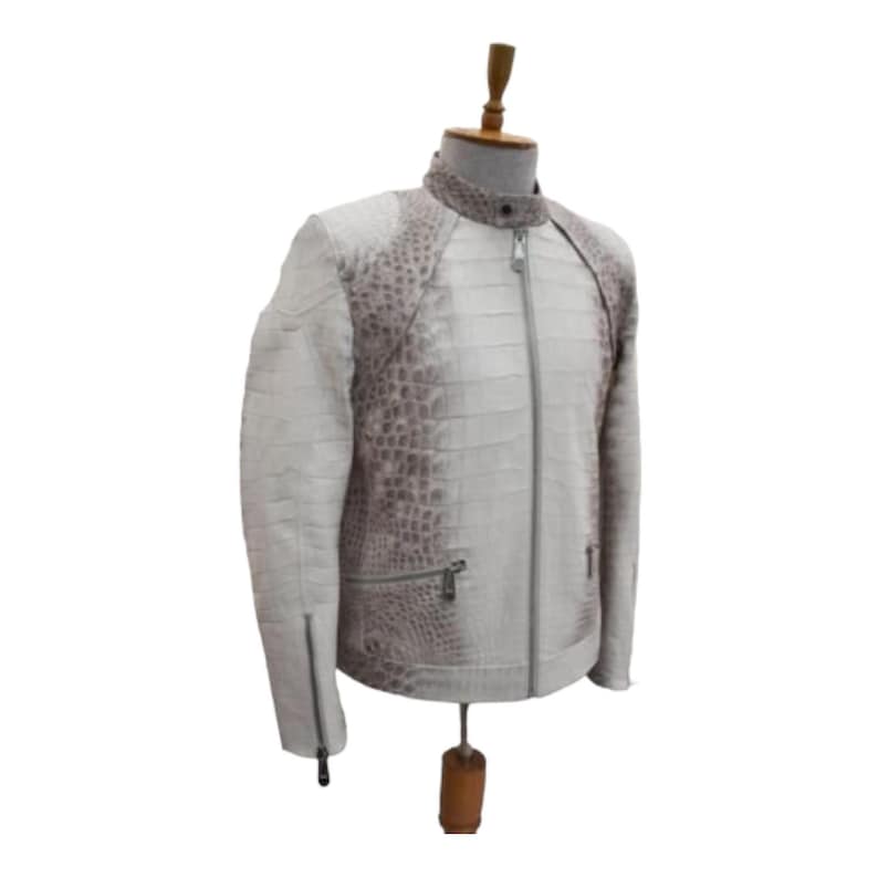 Puede incluir: Chaqueta de cuero blanca y gris con estampado de cocodrilo. La chaqueta tiene cierre de cremallera, cuello alto y bolsillos con cremallera. La chaqueta se exhibe en un maniqu&iacute;.