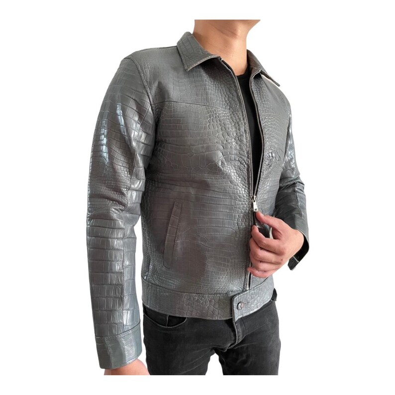 May include: A gray leather jacket with a crocodile skin texture. The jacket has a zipper closure, a collared neckline, and long sleeves. The jacket is a medium gray color and has a classic design.