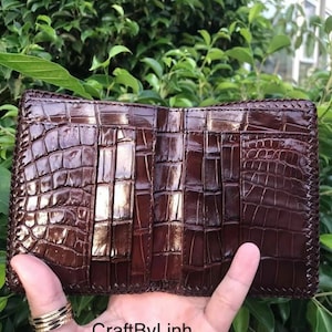 May include: A brown leather wallet with a crocodile pattern and multiple card slots. The wallet is open and the inside is visible. The text "CraftByLinh" is visible on the bottom of the image.