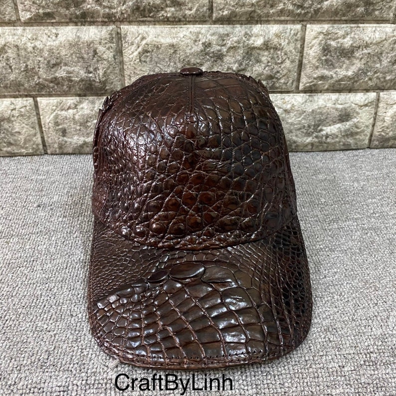 May include: A brown leather baseball cap with a crocodile skin pattern.