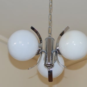 Può includere: Un lampadario a tre luci in cromo e bianco con una catena appesa al soffitto.