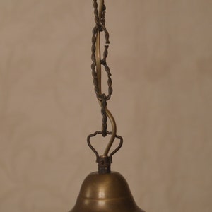 K&ouml;nnte beinhalten: Eine antike Deckenleuchte aus Messing und Glas mit einem cremefarbenen Glasschirm. Der Schirm hat einen gewellten Rand und ein dekoratives Muster.