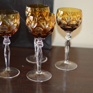 Puede incluir: Juego de cuatro copas de vino con tallo de color ámbar con un diseño de vidrio cortado.