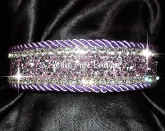 May include: A purple and silver dog collar with a row of sparkling crystals. The collar is decorated with a silver rope design and the text "Spoiled Pups Boutique".