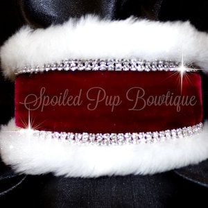May include: A pet accessory with a deep red velvet central section, trimmed with sparkling rhinestone and fluffy white faux fur. The text "Spoiled Pup Bowtique" is displayed on the velvet.