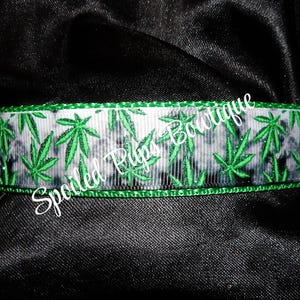 May include: Green and white ribbon with a marijuana leaf pattern. The ribbon has a green border.