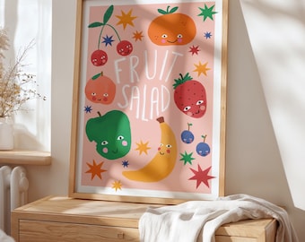 May include: A pink framed print with a fruit salad theme. The print features a variety of fruits with smiling faces, including a banana, apple, orange, strawberry, and cherries. The text "Fruit Salad" is written in white letters on a pink background.