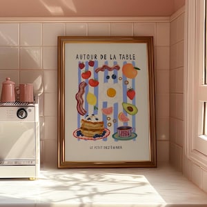 May include: A framed illustration of a breakfast scene with the text "Autour de la Table Le Petit Déjeuner" in a gold frame. The illustration features a blue and white striped background with various breakfast foods, including bacon, eggs, pancakes, fruit, and a cup of coffee.