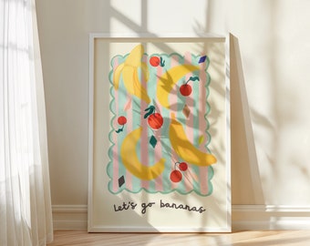 May include: A framed wall art print featuring a light green scalloped border over a pink and green striped background. The illustration displays yellow bananas, red cherries, and orange fruits with the text Let's go bananas at the bottom.