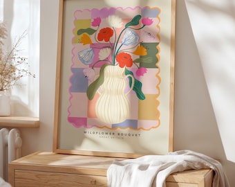 Könnte beinhalten: Ein gerahmter Kunstdruck mit einer cremefarbenen Vase, gefüllt mit einem bunten Wildblumenstrauß. Der Hintergrund besteht aus einem mehrfarbigen Karomuster mit gewelltem Rand. Der Text lautet WILDFLOWER BOUQUET GREAT BRITAIN.
