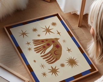 May include: Framed art print featuring a celestial design. The artwork showcases a stylized hand with star and crescent moon details, surrounded by various star shapes in shades of brown and red. The print is framed in a wooden frame with blue and brown borders.