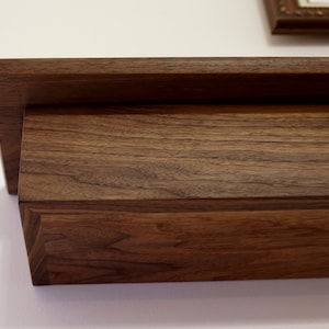 May include: A dark brown wooden shelf with a simple design. The shelf is made of solid wood and has a natural finish.