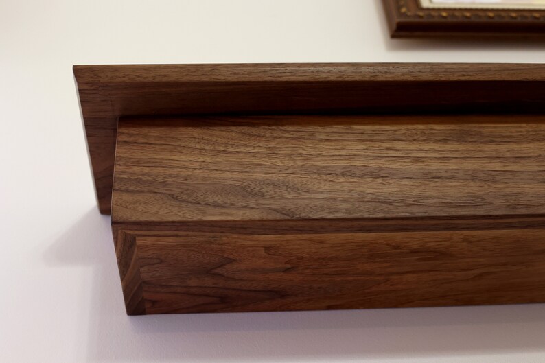 May include: A dark brown wooden shelf with a simple design. The shelf is made of solid wood and has a natural finish.