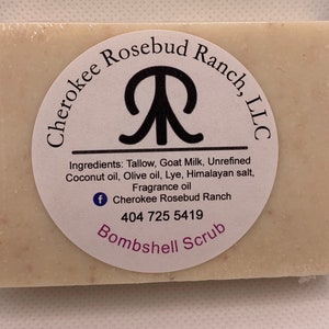 May include: A white bar of soap with a brown label that reads "Cherokee Rosebud Ranch, LLC" and "Bombshell Scrub". The label also includes the ingredients: Tallow, Goat Milk, Unrefined Coconut oil, Olive oil, Lye, Himalayan salt, Fragrance oil. A Facebook icon and phone number are also included on the label.