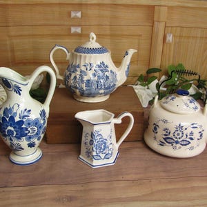 May include: A set of four blue and white ceramic tea and coffee serving pieces. The set includes a teapot, a creamer, a sugar bowl, and a pitcher.