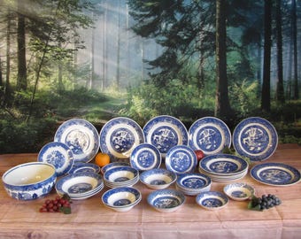 May include: A large collection of blue and white ceramic dinnerware featuring a traditional willow pattern. The set includes various sizes of plates, bowls, and saucers, all decorated with intricate oriental-style landscape illustrations.