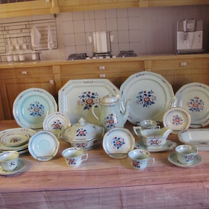 May include: A vintage set of blue and white floral china dinnerware, including plates, bowls, cups, saucers, a teapot, a sugar bowl, and a gravy boat. The set features a delicate floral pattern with pink and blue accents.