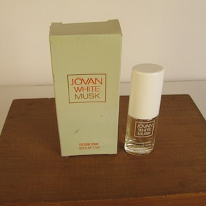 May include: A bottle of Jovan White Musk cologne spray with a white cap and a matching box. The box and bottle both feature the Jovan White Musk logo in a red rectangle. The bottle is 1 fl oz.