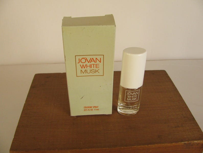 May include: A bottle of Jovan White Musk cologne spray with a white cap and a matching box. The box and bottle both feature the Jovan White Musk logo in a red rectangle. The bottle is 1 fl oz.