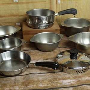 May include: A set of three ceramic mugs with a speckled, matte finish. The mugs are in shades of cream, light brown, and dark brown. Each mug has a simple, minimalist design and a rounded handle.