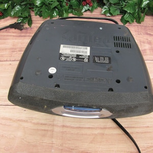 May include: Black DVD player with a silver trim and a power cord. The player has a label on the top that says "Sanyo".