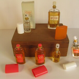 May include: Collection of vintage perfume bottles, including Jovan White Musk, Lady Stetson, and Wild Musk. The bottles are various shapes and sizes, with amber and clear glass, and red, white, and orange accents. Some bottles have their original packaging.