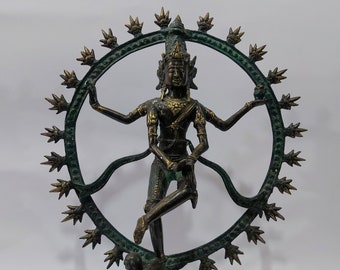 May include: A bronze statue of a Hindu deity, possibly Shiva, in a dancing pose. The statue is standing on a circular base with a smaller figure at the bottom. The deity is surrounded by a circular halo with decorative spikes.