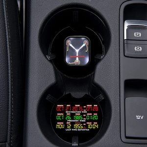 May include: A black car cup holder with a red and green digital display that reads "MONTH DAY YEAR HOUR MIN", "OCT 21 2015 07:28", "DESTINATION TIME", "OCT 26 1985 01:20", "PRESENT TIME", "NOV 12 1955 10:04", and "LAST TIME DEPARTED".