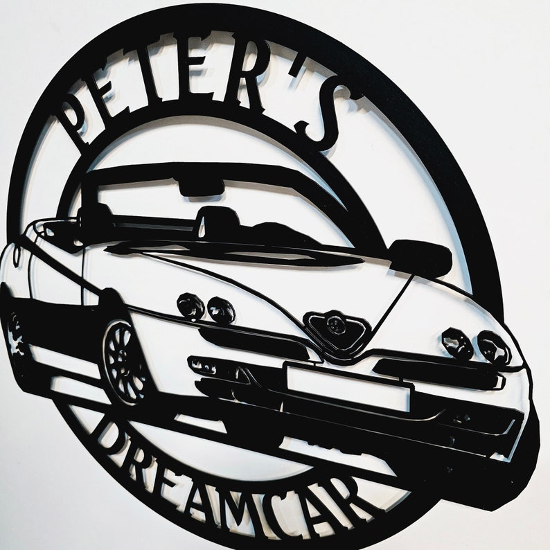 May include: Black and white metal silhouette of a car with the words "Peter's Dreamcar" around the outside.