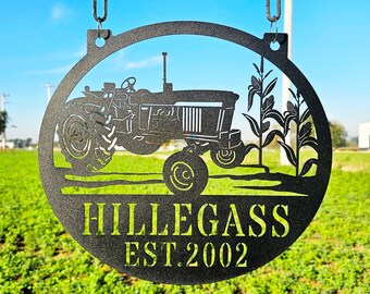 May include: Black metal sign featuring a silhouette of a tractor and corn stalks. The sign reads "Hillegass Est. 2002".