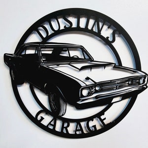 May include: Black and white metal sign with the text "Dustin's Garage" in a circle. A black silhouette of a classic car is in the center of the circle.