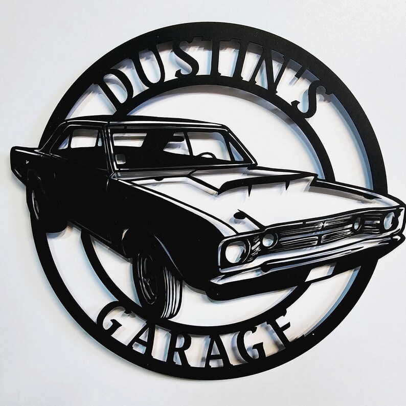 May include: Black and white metal sign with the text "Dustin's Garage" in a circle. A black silhouette of a classic car is in the center of the circle.