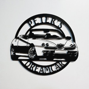 May include: Black metal silhouette of a convertible car with the words "Peter's Dreamcar" around it.